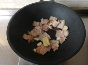 然后下姜片和蒜片（蒜粒切成片）下锅一起翻炒爆香。略微煸炒一会，让肉微微发黄，带焦的感觉，这样肉最后成品出来焦香四溢，超级好吃，而且一点不腻！