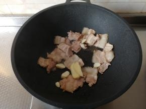 然后下姜片和蒜片（蒜粒切成片）下锅一起翻炒爆香。略微煸炒一会，让肉微微发黄，带焦的感觉，这样肉最后成品出来焦香四溢，超级好吃，而且一点不腻！