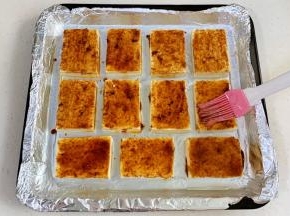 给豆腐片抹上酱汁。