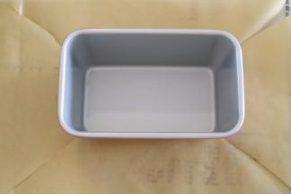 准备一个长方形蛋糕吐司模，底部放上一张硬点油纸，四个角剪开。