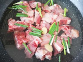 排骨凉水入锅，放入小葱段和生姜片，加入一勺料酒，烧开焯水2-3分钟。