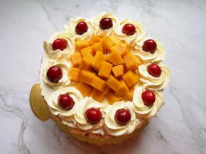 放上最后一层蛋糕片，表面薄薄的抹上一层奶油，挤上一圈奶油花，放上樱桃装饰，中间位置放上大块的火龙果和芒果。