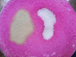 将榨好的牛奶火龙果汁倒入盆里，放糖和发酵粉搅拌均匀。