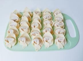 取一张馄饨皮放入馅料，包成元宝状。