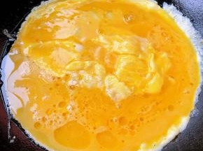 锅中倒入底油加热倒入蛋液炒至鸡蛋八成熟