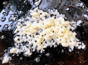 另起锅倒入底油加热放入蒜粒爆香