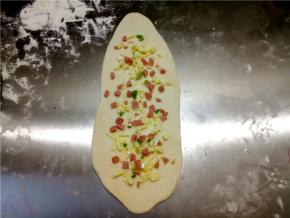 撒火腿粒、芝士和葱花，然后从宽的一头卷起，收口捏紧，可以沾一点水。