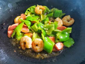 锅中热油，放虾仁炒至变红，加入切好的火腿，青椒炒熟，