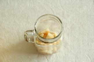 将腌渍好的蜜桃块舀入碗杯子中。