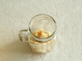 将腌渍好的蜜桃块舀入碗杯子中。