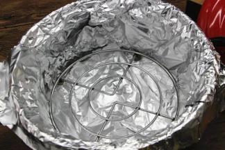 4.拿出砂锅，不要用水洗，切忌，用干净的干纸巾擦一下即可，底部铺上两层锡纸，防止烤肉滴下来的油水弄脏砂锅，放入一个矮脚的三脚架