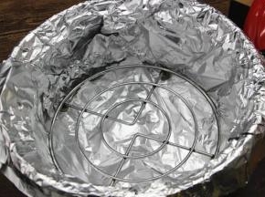 4.拿出砂锅，不要用水洗，切忌，用干净的干纸巾擦一下即可，底部铺上两层锡纸，防止烤肉滴下来的油水弄脏砂锅，放入一个矮脚的三脚架