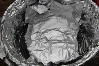 5.在三脚架上放入一块锡纸，四周像盘子边缘一样折起来，防止烤肉时烤出的水分滴落到砂锅里