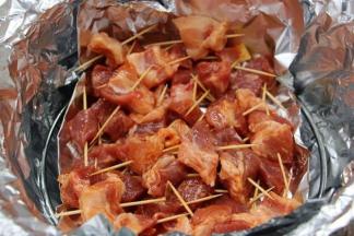 6.将腌制好的肉块用牙签一一串好，刷上一层油，均匀的摆入烤架上的锡纸盘