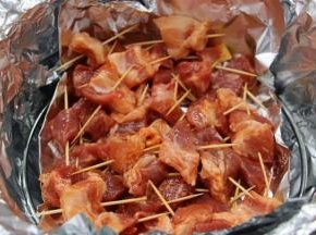 6.将腌制好的肉块用牙签一一串好，刷上一层油，均匀的摆入烤架上的锡纸盘