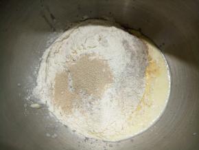 将除黄油、葡萄干之外的材料倒入厨师机打面桶中，低速开始打面。我用的酸奶是袋装的，比牛奶稍微稠一点点。