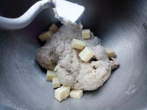 打到面粉成团，桶壁干净，加入软化的黄油，继续打面。