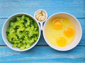 苦瓜洗净后，将里面的瓤掏干净切片，取3个鸡蛋打散搅拌均匀放在碗中备用。 大蒜去皮拍扁。