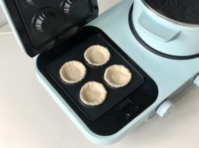 东菱三明治机装好果挞盘，预热2分钟，然后把手抓饼胚放进去。
