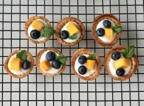 在酸奶上放入蓝莓和芒果丁，插上薄荷叶装饰。