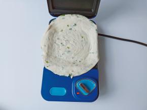 三明治机提前预热三分钟，取一张手抓饼撕去外边的膜放入三明治机里。