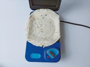 三明治机提前预热三分钟，取一张手抓饼撕去外边的膜放入三明治机里。