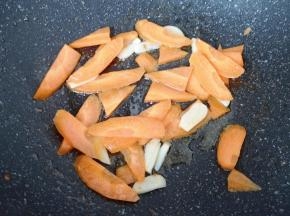 锅底留余油烧热，下入蒜片炒香，下入胡萝卜翻炒至变色。