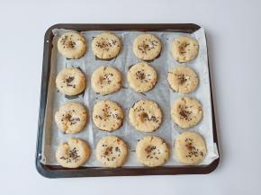 烤盘垫上油纸，将面团分成16个小剂子，拿一个剂子放在手心搓圆，用手心轻轻按扁一下，再依次码在烤盘上，用食指在面团中间轻轻按一下，撒上黑芝麻或者白芝麻都可以。