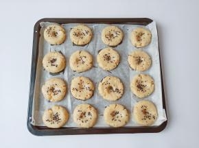 烤盘垫上油纸，将面团分成16个小剂子，拿一个剂子放在手心搓圆，用手心轻轻按扁一下，再依次码在烤盘上，用食指在面团中间轻轻按一下，撒上黑芝麻或者白芝麻都可以。