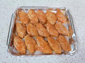炸篮里铺上锡纸，刷上一层食用油，将腌制好的鸡翅摆在上面。