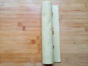 将放上肉馅的千张卷起来，淀粉里面加一点点水，抹在空出来的地方，继续卷好。