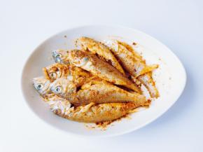 带上一次性手套把调料粉跟鱼抓均匀，让每一条鱼都裹上粉，在淋上一勺芝麻油增加香味。