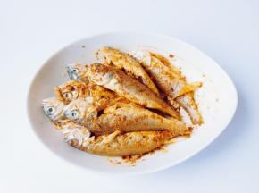 带上一次性手套把调料粉跟鱼抓均匀，让每一条鱼都裹上粉，在淋上一勺芝麻油增加香味。