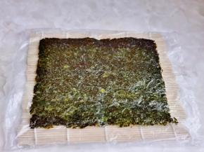 准备寿司卷席，铺上一张保鲜膜，再放上一张海苔。