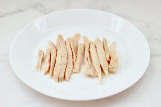 把加热好的鸡胸肉，用刀切成粗条。