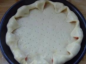 5.烤盘抹上一层黄油，发酵好的面团，按压排气，松弛10分钟；  放入烤盘中慢慢推开，在匹萨的饼皮周围均匀的摆上一圈香肠，  将香肠的空隙处的饼皮轻轻的拉长并包住香肠，按压在里侧；  用叉子扎眼