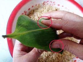 右手把粽叶盖上来，两边红框处要往下折1厘米左右。