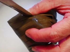 把上半部分粽叶盖住糯米顺着一个方向绕成一粽子形状