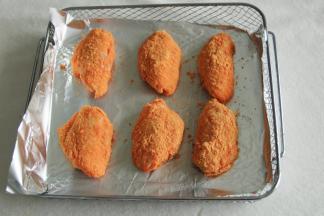 腌制好了鸡翅，准备好咸蛋黄风味调料。带着手套拿起一只鸡翅，裹上厚厚一层咸蛋黄调料。然后排入烤篮，记得垫上锡纸。