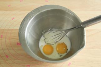 蛋黄放入无水干净盆中，倒入牛奶、酸奶和玉米油，用蛋抽搅打均匀。