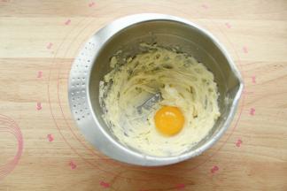 用刮刀稍微混合一下，看不见糖粉即可，防止打发时候糖粉飞溅。用电动打蛋器中速顺一个方向进行打发。打到黄油变白，蓬松羽毛状。如图，体积明显变大，盆边的用刮刀刮下，要全部打到。然后加入一个常温蛋黄。