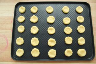 此时可以预热烤箱，上下180度。戴上PVC手套，将面团分成12克一个，搓圆，放在烤盘上，排好，中间用大拇指按扁。