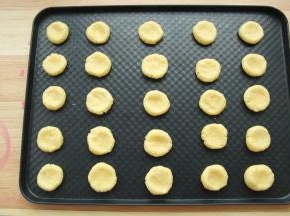 此时可以预热烤箱，上下180度。戴上PVC手套，将面团分成12克一个，搓圆，放在烤盘上，排好，中间用大拇指按扁。