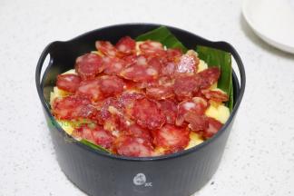 把大米、糯米、土豆、少许盐、花生油，搅拌均匀倒入垫好的粽叶蒸笼上，最上面一层铺上腊肠。