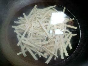 烧一锅水，水开后，下豆皮丝焯水一分钟。