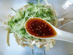 青瓜丝滤去腌渍出来的水，倒入豆皮碗中，加入2汤匙辣椒油。