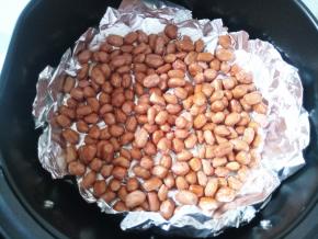 倒入拌过油的花生米，尽量铺平。炸锅180度先烤5分钟。可以听到噼啪声，那是花生皮被烤的开裂的声音。