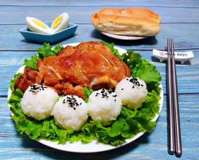 盘中铺上生菜摆上鸡腿肉米饭握成圆团撒上黑芝麻就大功告成了