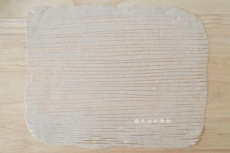 取一个面剂子，擀成长方形，面片上刷上一层油，用刀划出一条条的丝，头部可以留少许不切断。