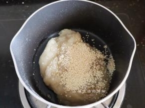 熄火后把熟的糯米粉倒入锅里，快速拌匀，此时糯米粉就会粘成团了，倒入熟芝麻拌匀，盖上保鲜膜放凉后分成12份。